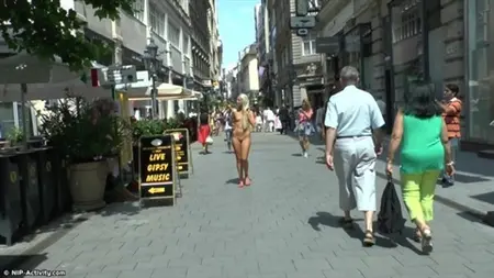 Naga blondynka spaceruje wzdłuż ruchliwych ulic